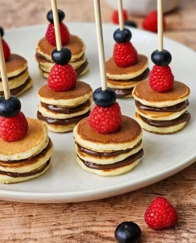 Mini pancakes apilados con crema de chocolate y frutos rojos